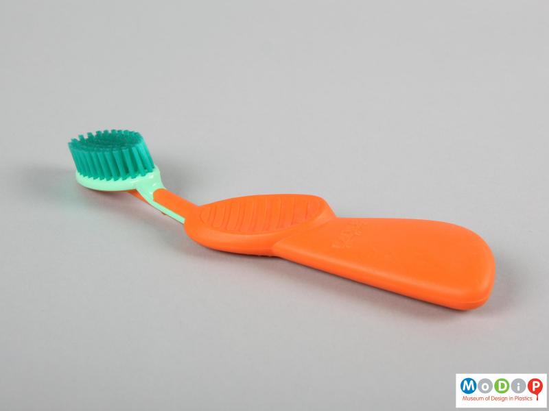 Side view of a toothbrush showing the large handle and thumb recess.