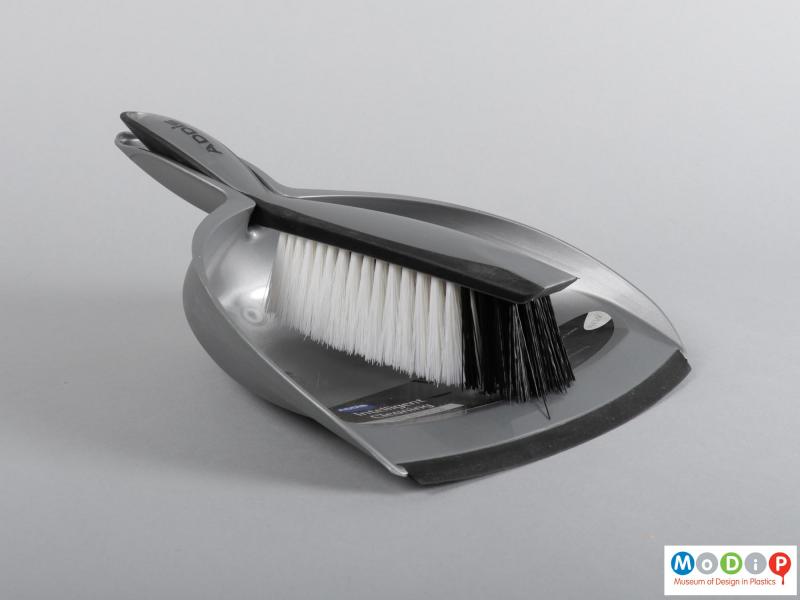 Side view of a dustpan and brush showing them clipped together.