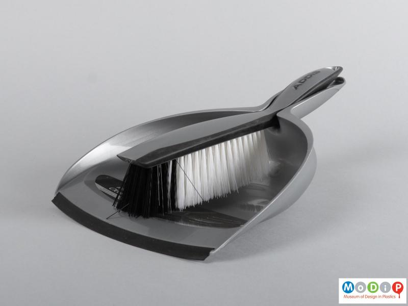 Side view of a dustpan and brush showing them clipped together.