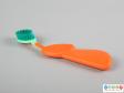 Side view of a toothbrush showing the large handle and thumb recess.