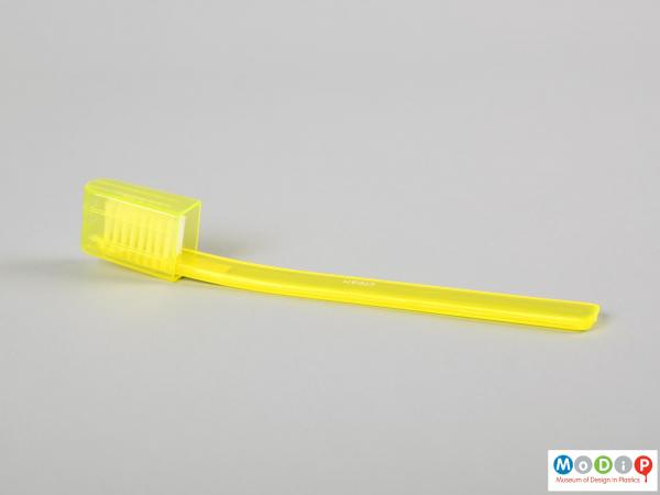 Side view of a toothbrush showing the slender handle.