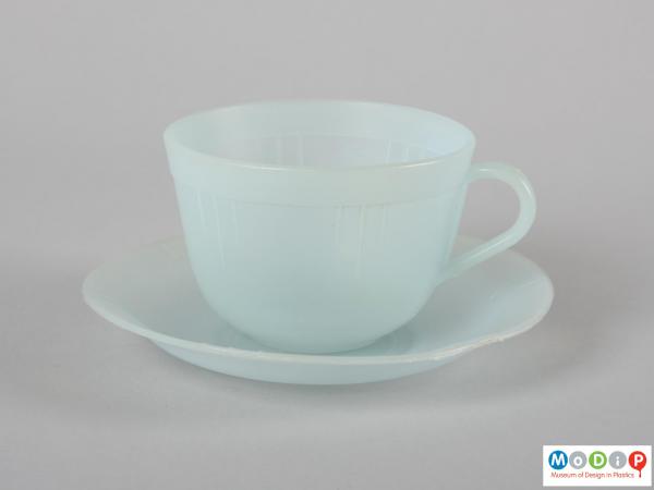 Side view of a cup and saucer showing the moulded line decoration around the cup.