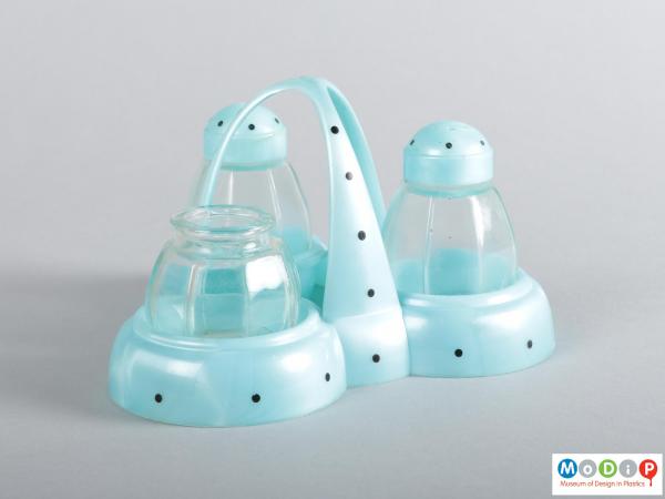 Side view of a cruet set showing the domes handle and glass pots.