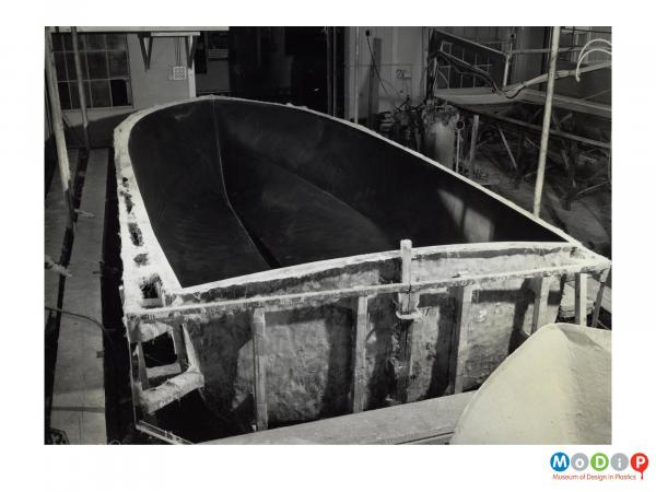 Scanned image showing a small boat being built.