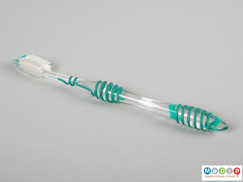 Side view of a toothbrush showing the spiral grip on the handle.