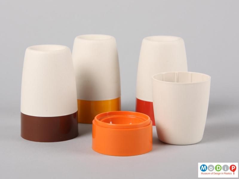 Side view of four Tupperware egg cups showing one cup with the cover removed.  The base shows a ridge fo the cover to sit on whilst the inside of the cover has gripping ribs.