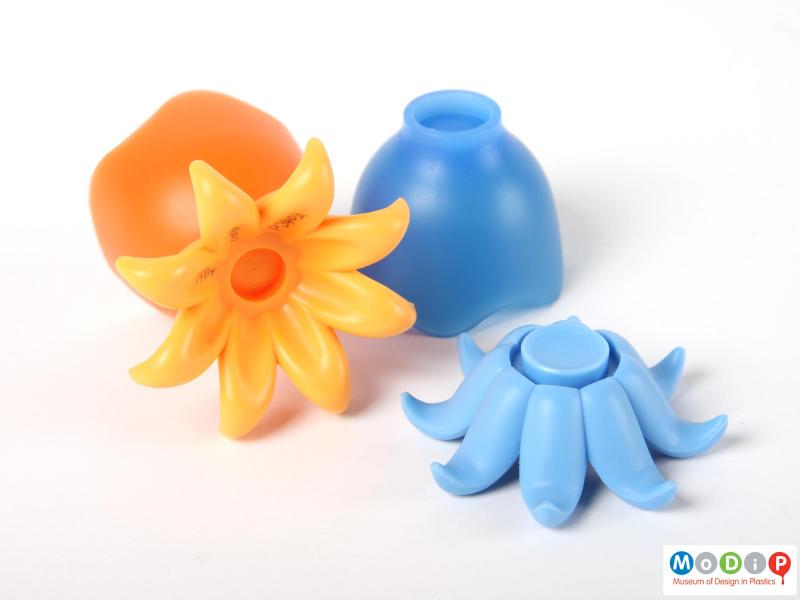 Side view of a pair of Living Gear octopus egg cups showing the orange cup laying on its side to reveal the base and the blue cup separate from its base.