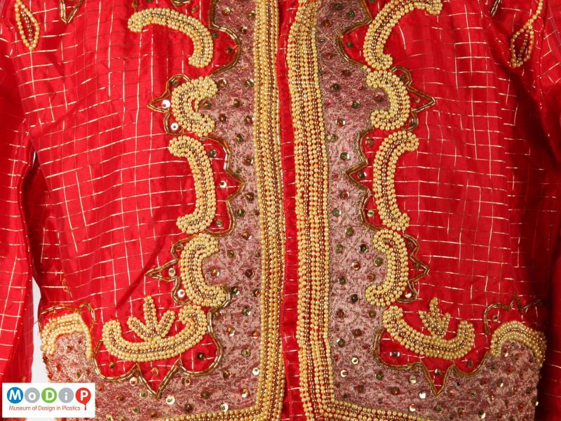 Close view of part of a suit showing the embellishment on the jacket.