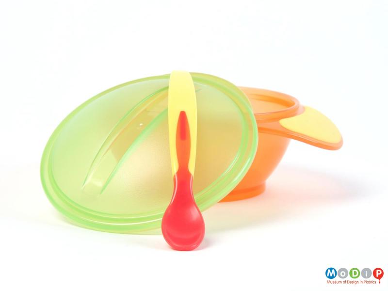 Side view of a Tommee Tippee weaning set showing the spoon and lid leaning on the bowl.