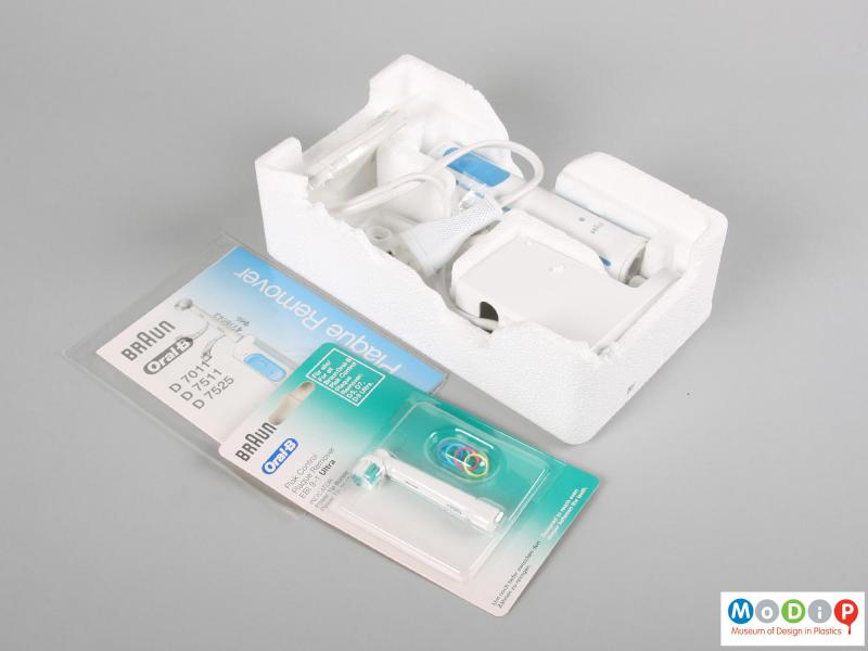 Top view of an electric toothbrush showing all the components in part of the packaging.