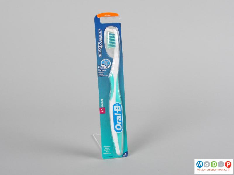 Front view of a packaged toothbrush showing the ergonomic shape of the handle and head.