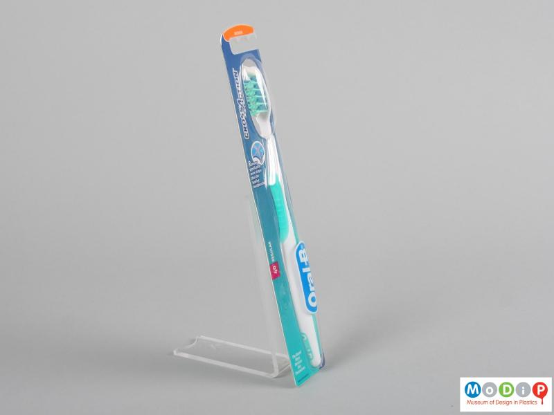 Side view of a packaged toothbrush showing the ergonomic shape of the handle and head.
