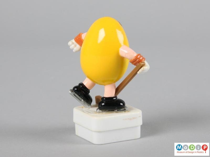 Side view of a yellow M&M figure showing the plain back.