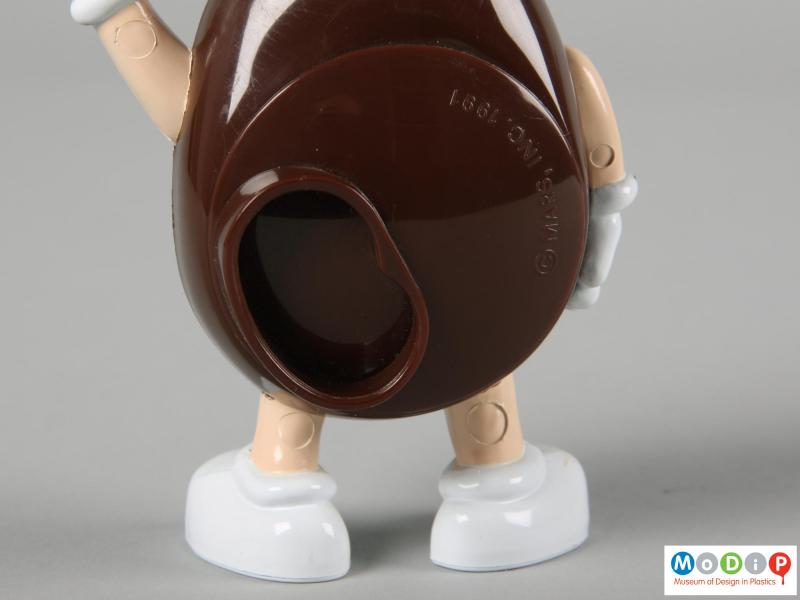 Close view of a brown M&M figure showing the back plate closed.