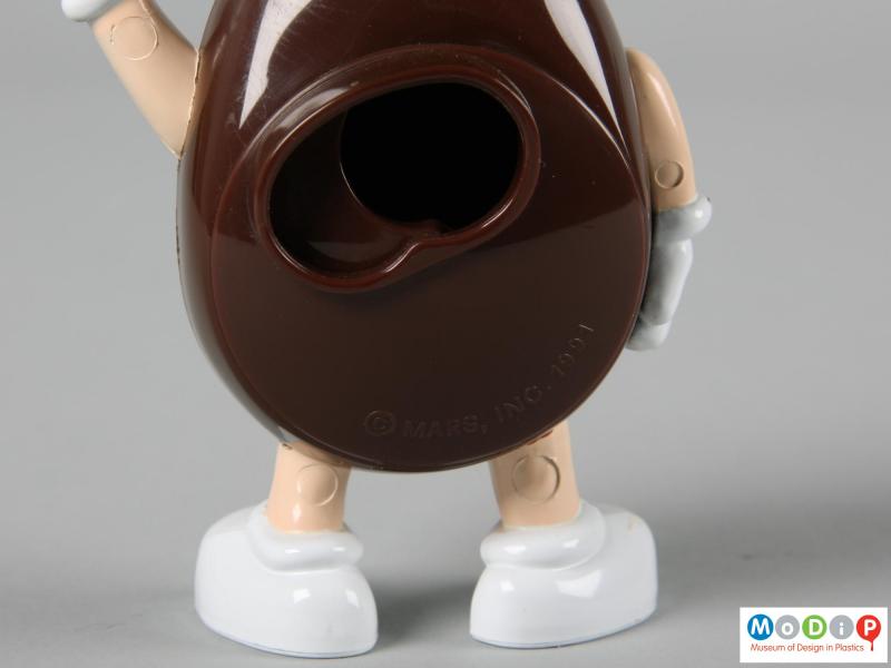Close view of a brown M&M figure showing the back plate open.