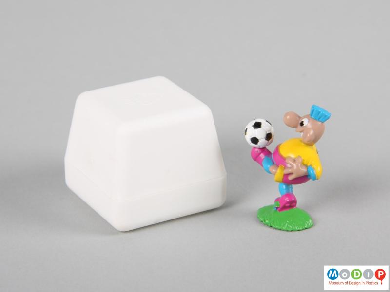 Side view of a football figure showing the football on the foot of the figure and the side of the box.