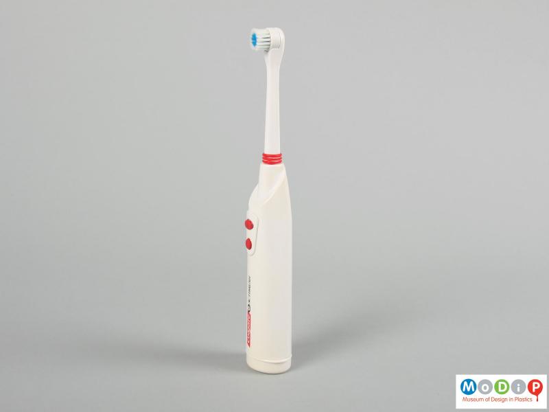 Side view of a toothbrush showing the round head and control buttons.