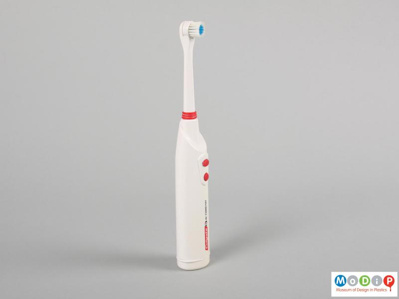 Side view of a toothbrush showing the round head and control buttons.