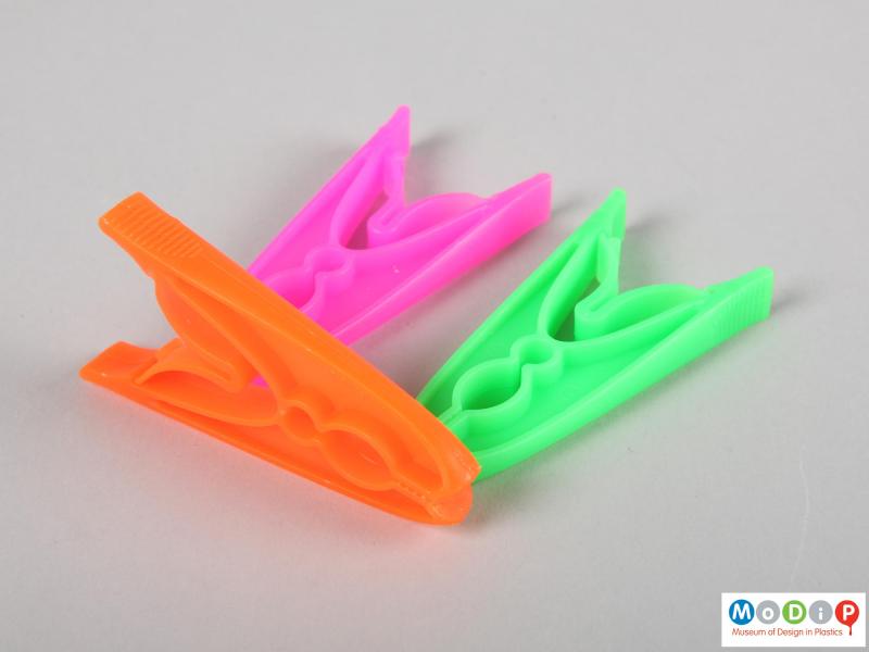 Side view of a packet of clothes pegs showing the finger grips on the ends.