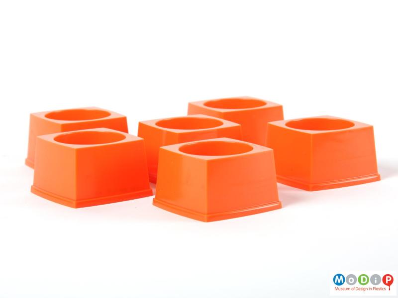 Side view of six stackable egg cups showing the sqaure shape and straight sides of the cups.