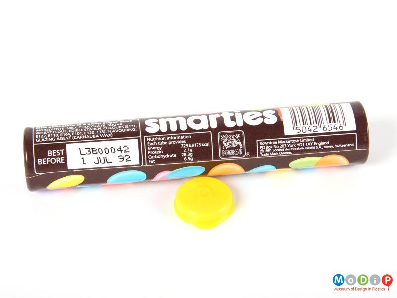 Side view of a Smarties tube showing the printed decoration and the inside of the lid.