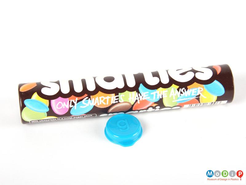 Side view of a Smarties tube showing the printed decoration and the inside of the lid.