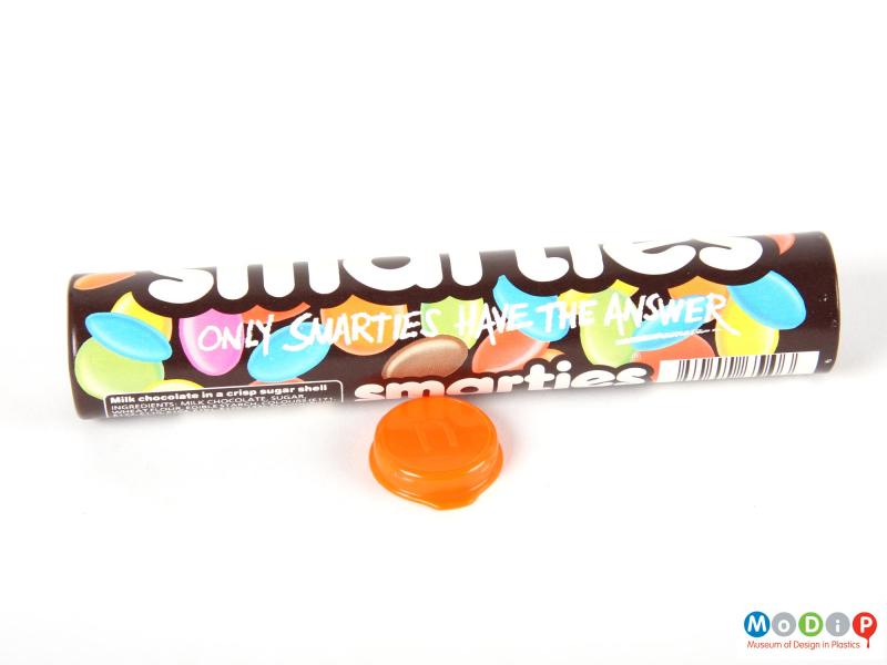 Side view of a Smarties tube showing the printed decoration and the inside of the lid.
