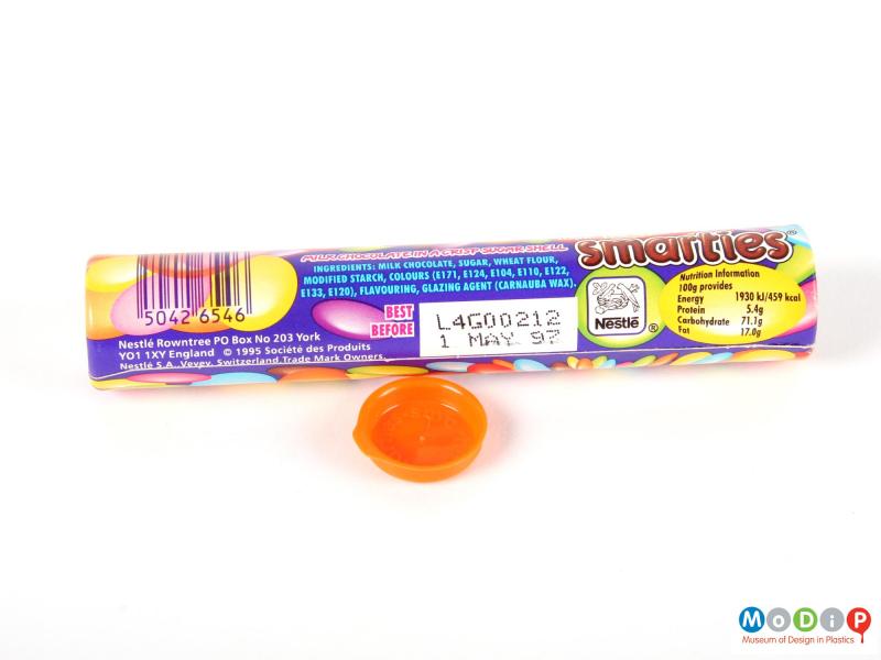 Side view of a Smarties tube showing the printed decoration and the inside of the lid.