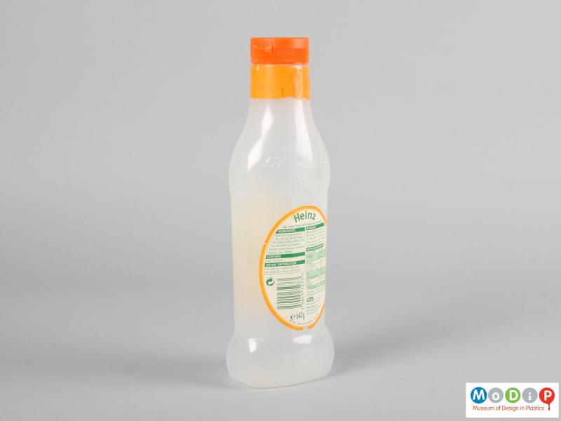 Rear view of a salad cream bottle showing the orange cap and translucent body.
