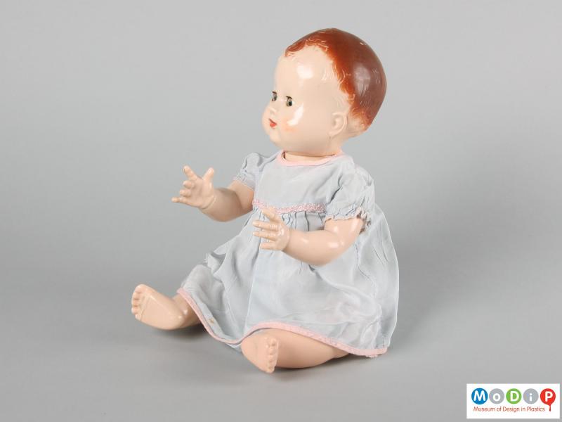 Side view of a Pedigree doll showing the doll in a seated position with arms foward and eyes open.