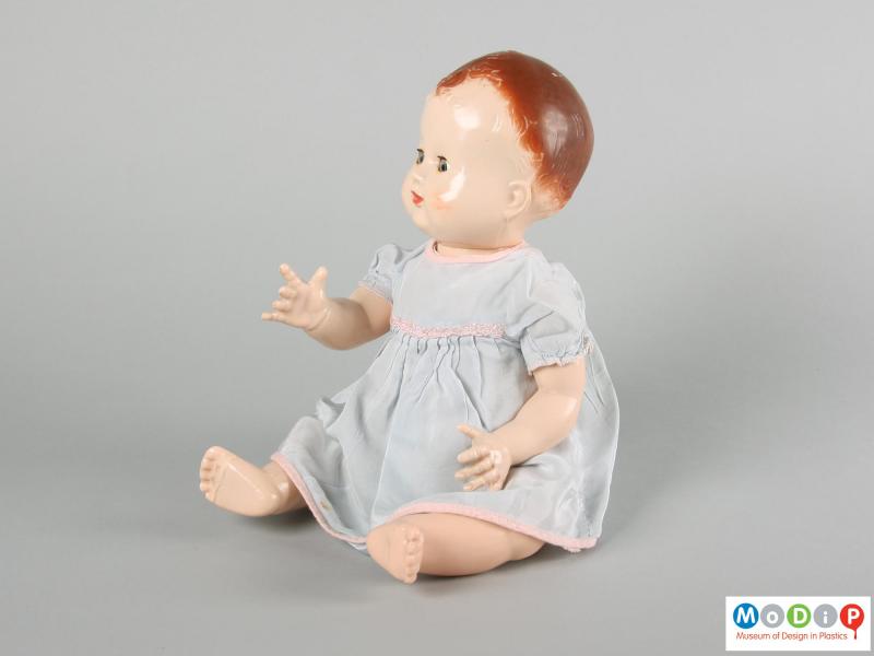 Side view of a Pedigree doll showing the doll in a seated position with one arm foward and one down by her side.