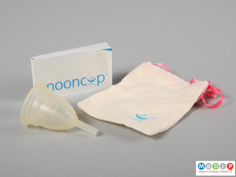 Side view of a menstrual cup showing the protective bag and instruction booklet.