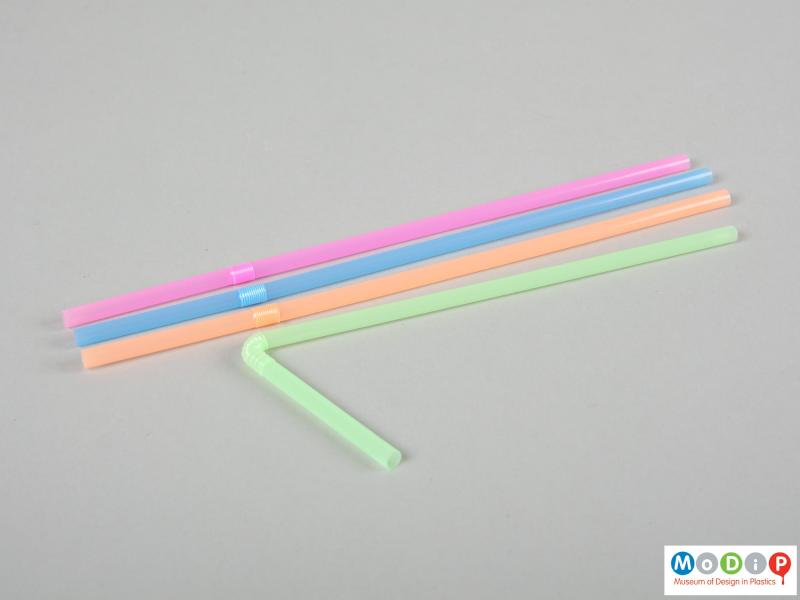Side view of a box of drinking straws showing one of the straws extended and bent.