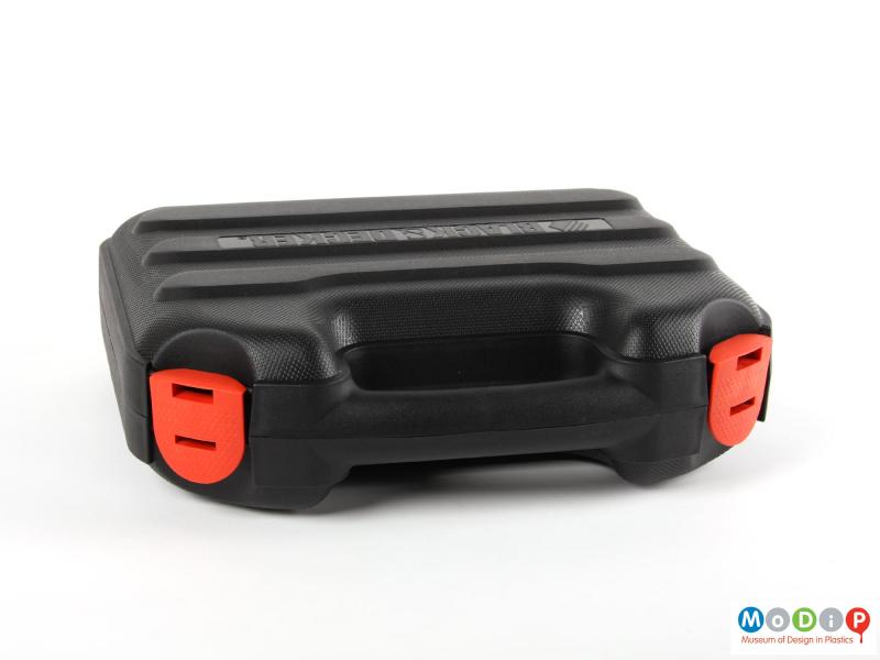 Top view of an electric drill showing the orange clips on the black carry case.