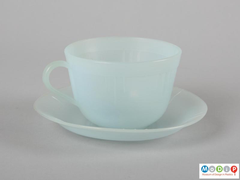 Side view of a cup and saucer showing the moulded line decoration around the cup.