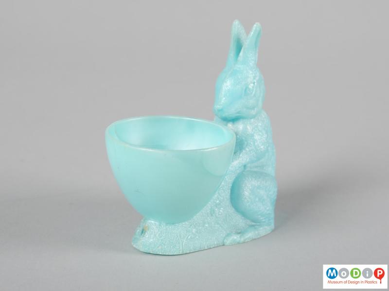 Side view of an egg cup showing the rabbit sitting behind the cup.