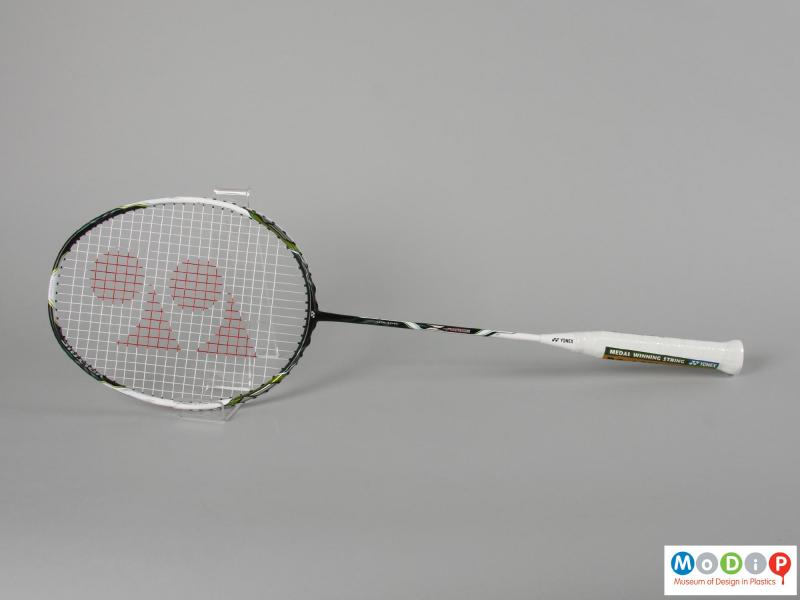 Side view of a badminton racket showing the egg shaped head and long, thin handle.