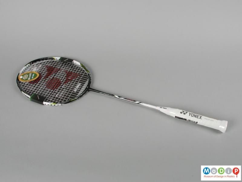 Side view of a badminton racket showing the printed logo on the strings.