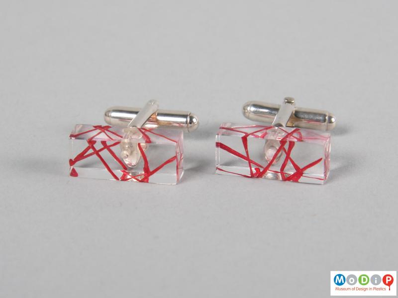 Front view of a pair of cuff links showing the red decoration.