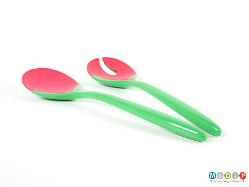 Side view of a pair of salad servers showing the long, slender handles.