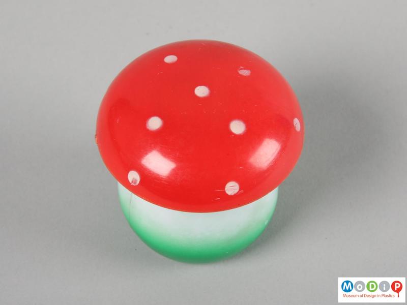 Top view of a set of tiddlywinks showing the red and white spotted lid.