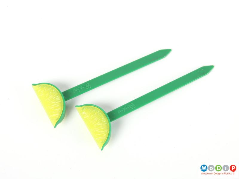 Side view of two swizzle sticks showing the lime sections and flat sticks.