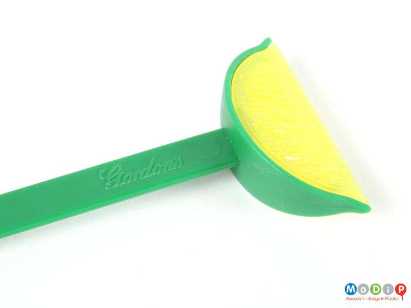 Close view of a swizzle stick showing the lime wedge.