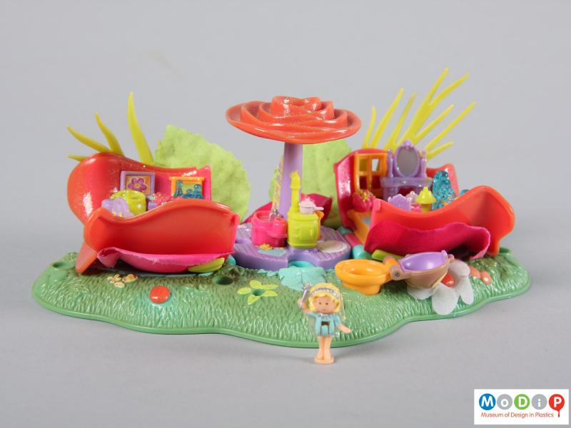 Side view of a Polly Pocket toy showing the small doll with the house behind.