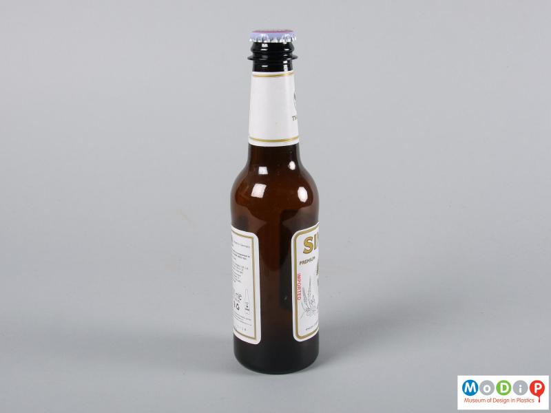 Side view of a bottle showing the adhesive labels and metal cap.