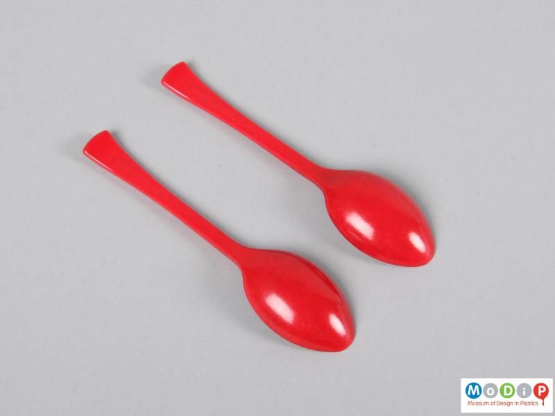Underside view of a pair of teaspoons showing the flaring handles and oval bowls,