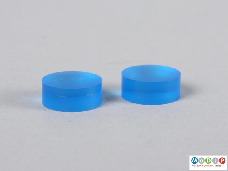 Side view of two blue contact lens buttons showing the thickness.