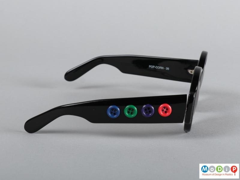 Side view of a pair of sunglasses showing the buttons on the arms.