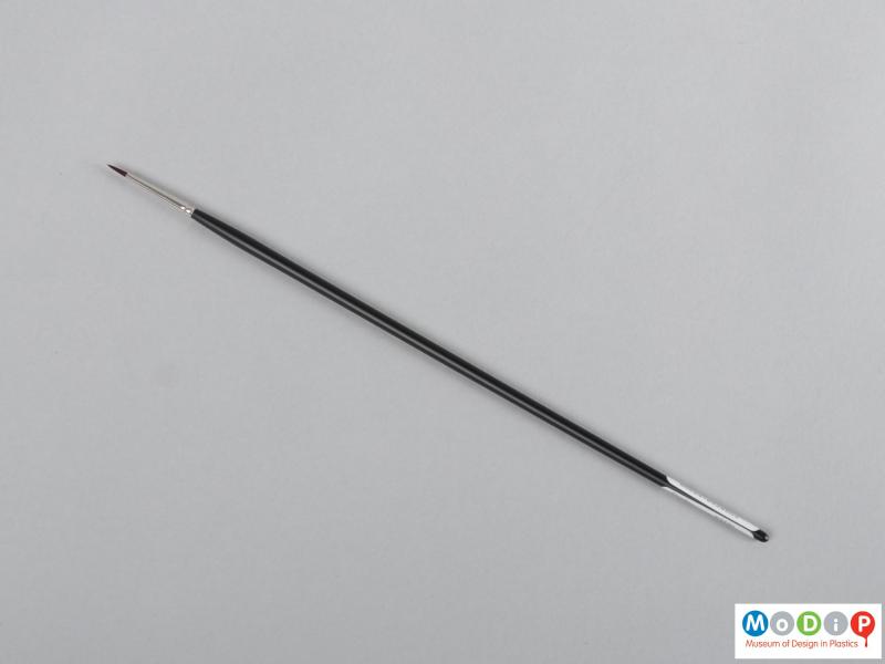 Top view of a brush showing the long handle and pointed head.