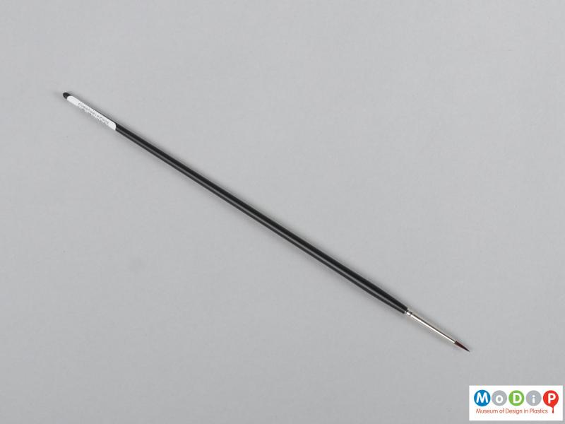 Top view of a brush showing the long handle and pointed head.